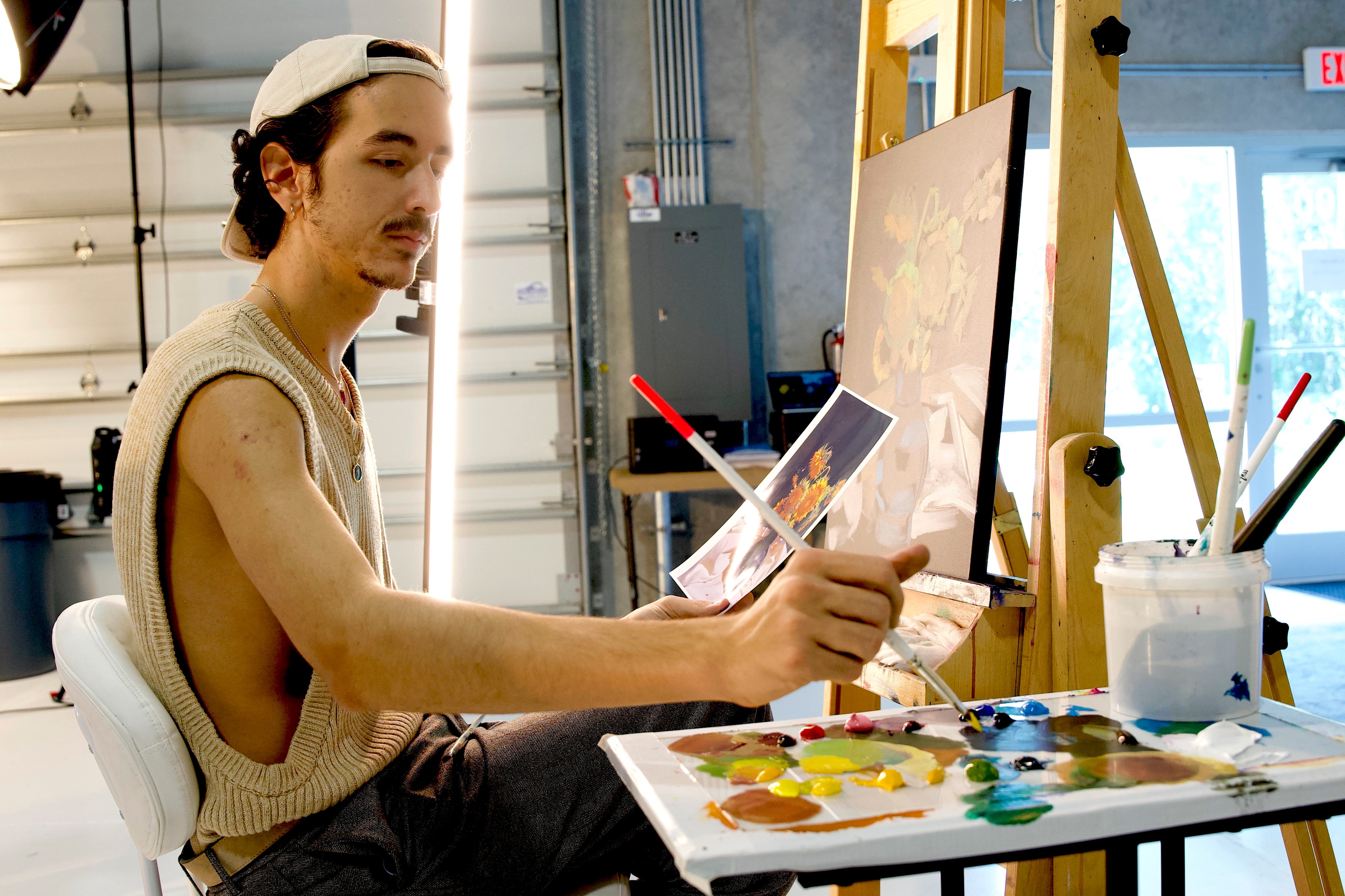 Man sitting in front of easel painting 