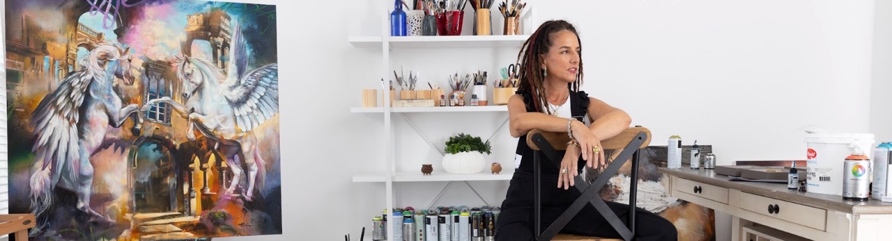 Elli Milan sitting in chair in art studio