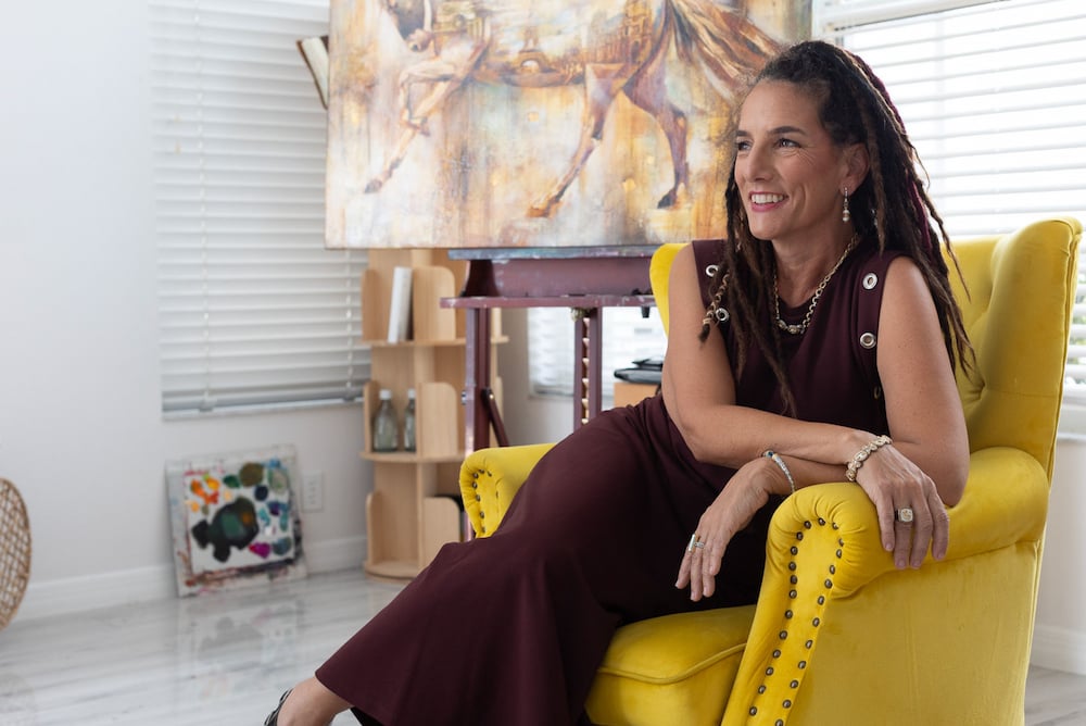 Woman sitting in yellow chair with painting in room
