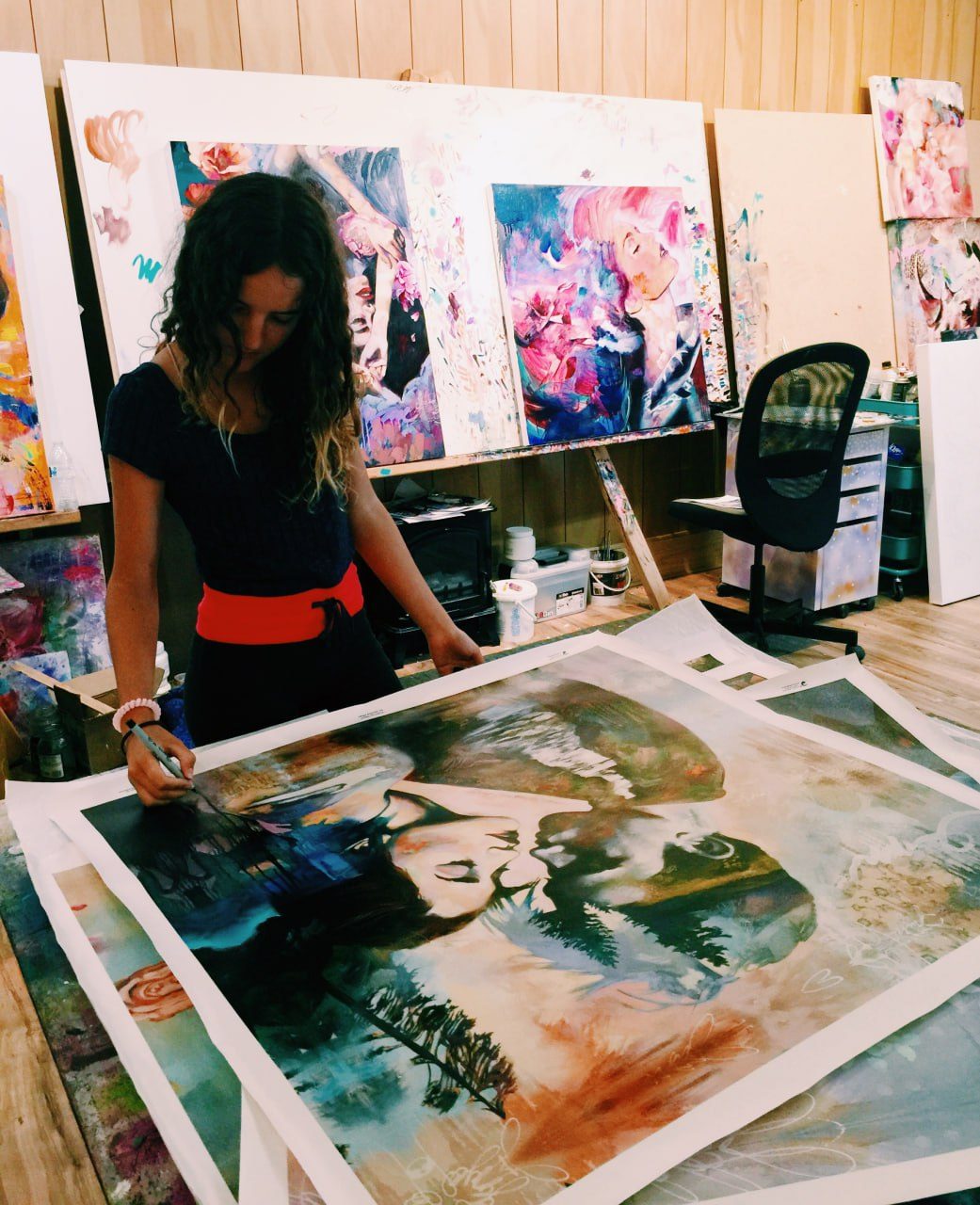 Several of Dimitra Milan's paintings in progress, laid out on a table