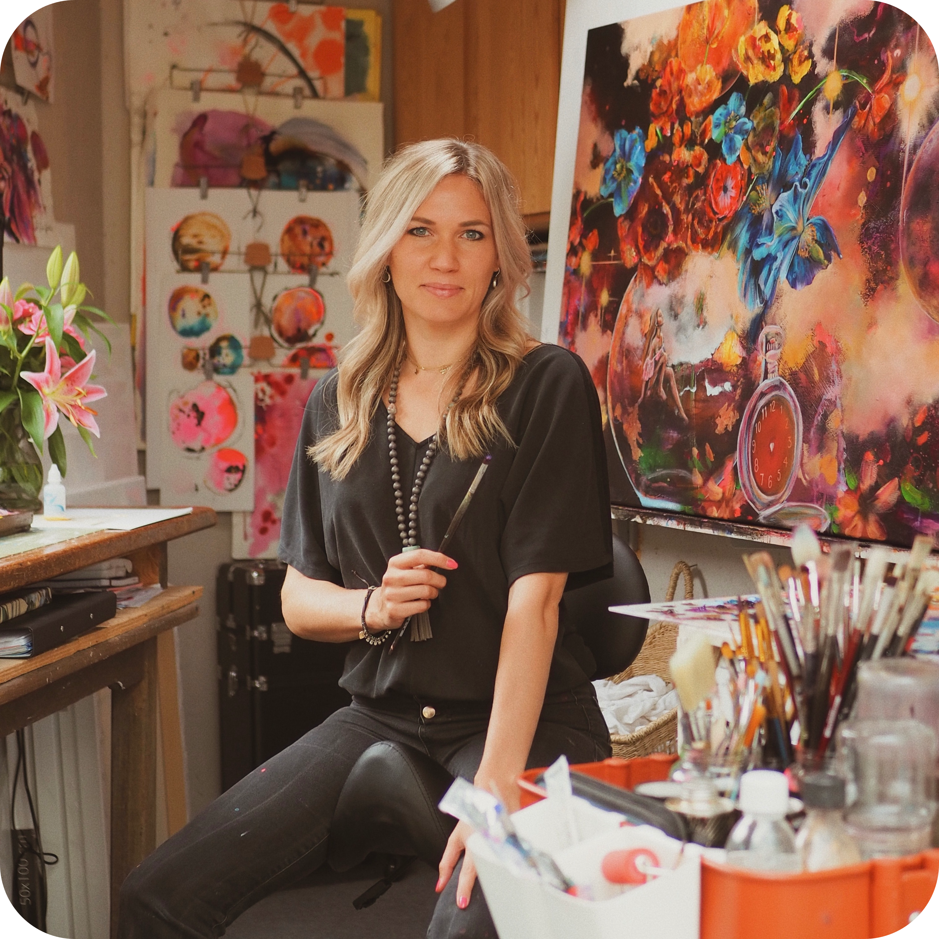 Woman sitting in art studio with colorful paintings around