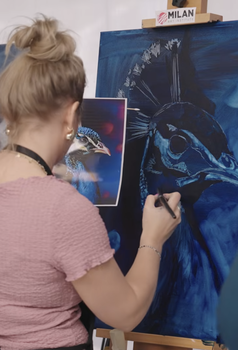 Woman painter painting with paper source a blue peacock