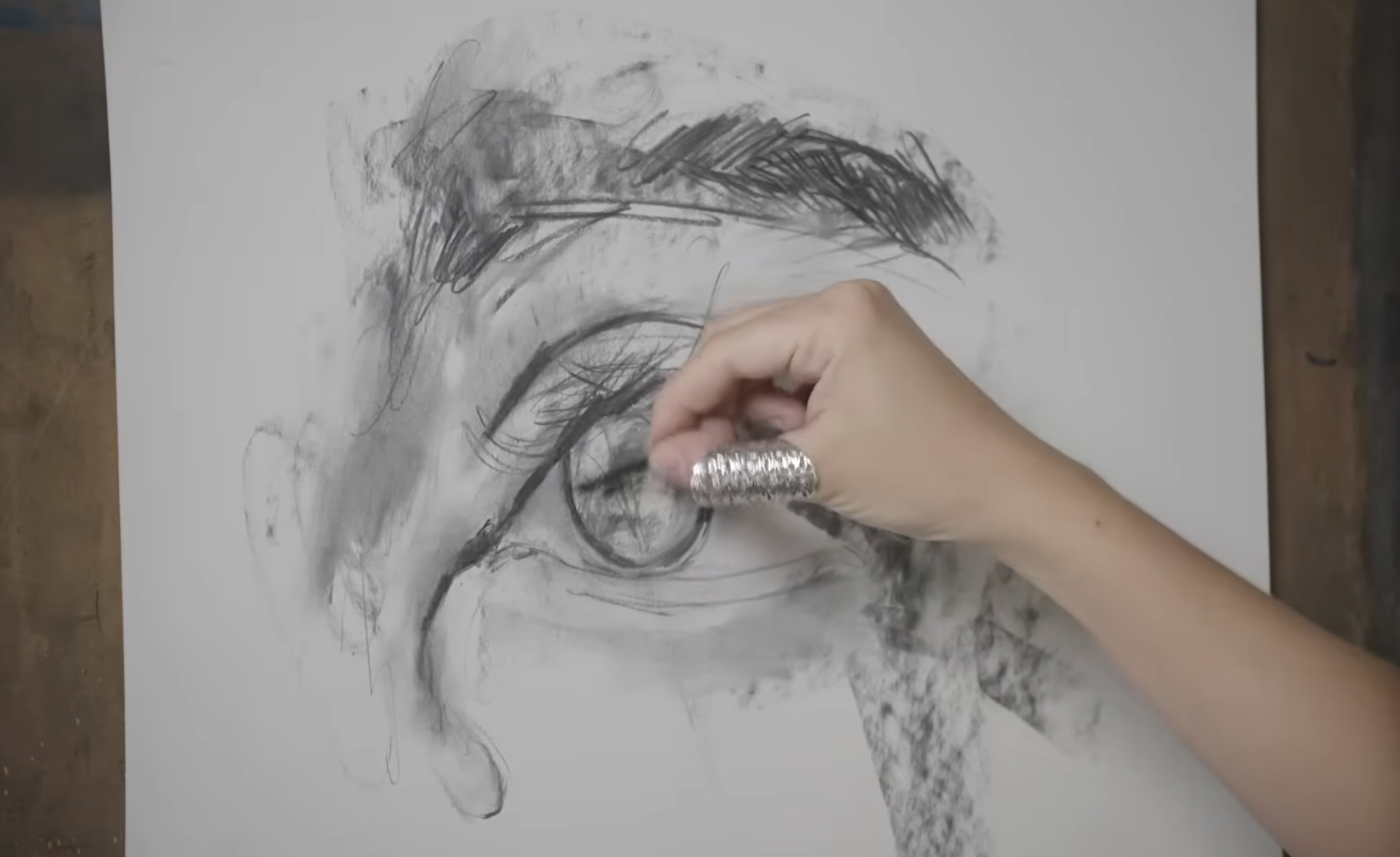 Hand sketching eye with charcoal on paper