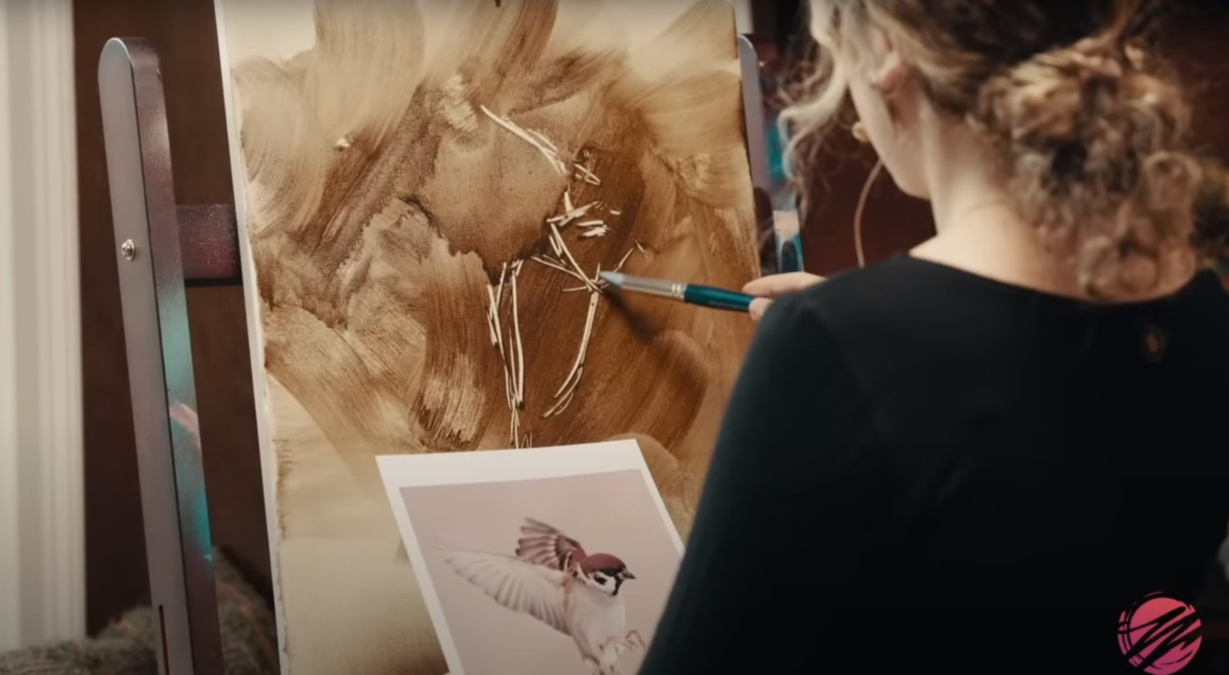 woman subtracting oil paint with tool on canvas in black shirt