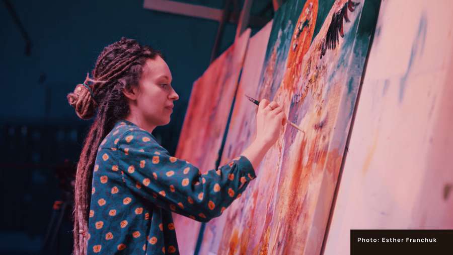 Woman in blue painting on a pink canvas