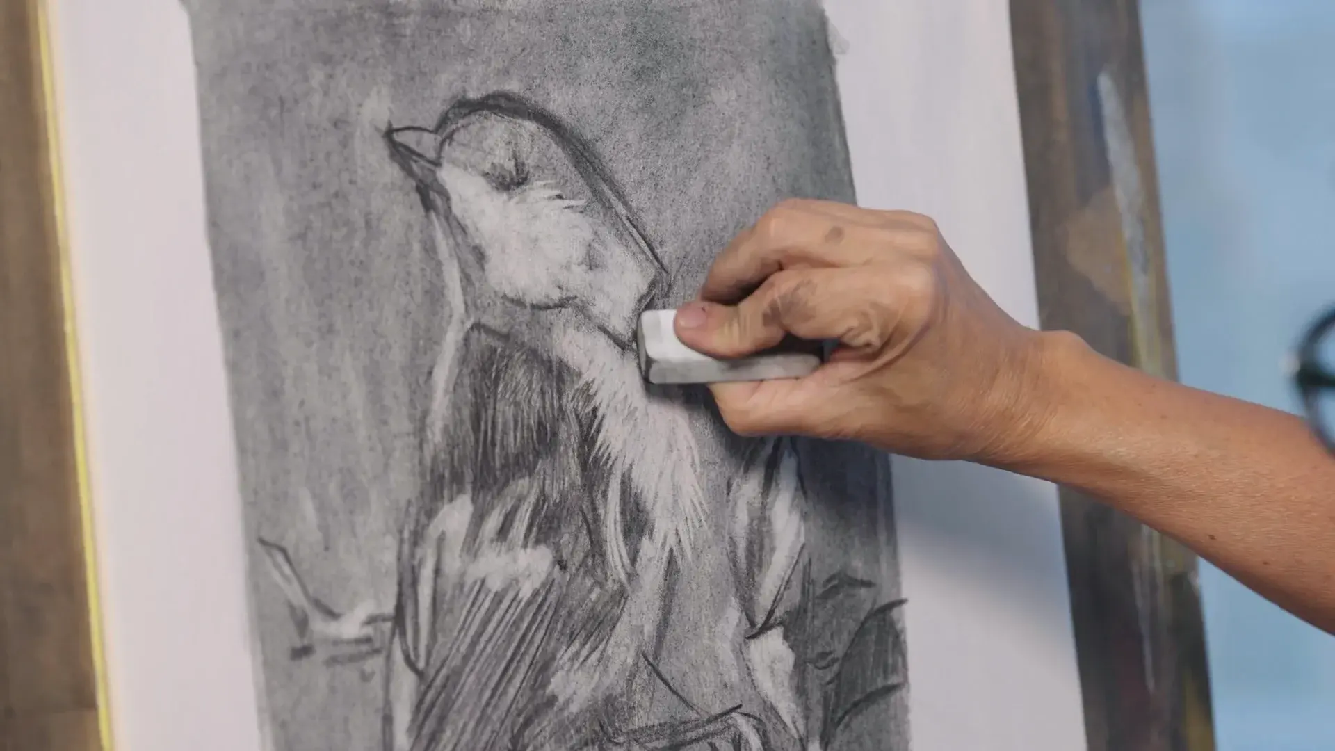 Elli lifting highlights out of the charcoal bird with an eraser