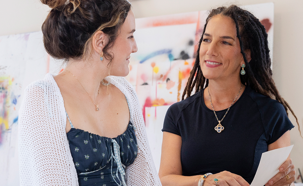 Woman looking at each other paintings in background