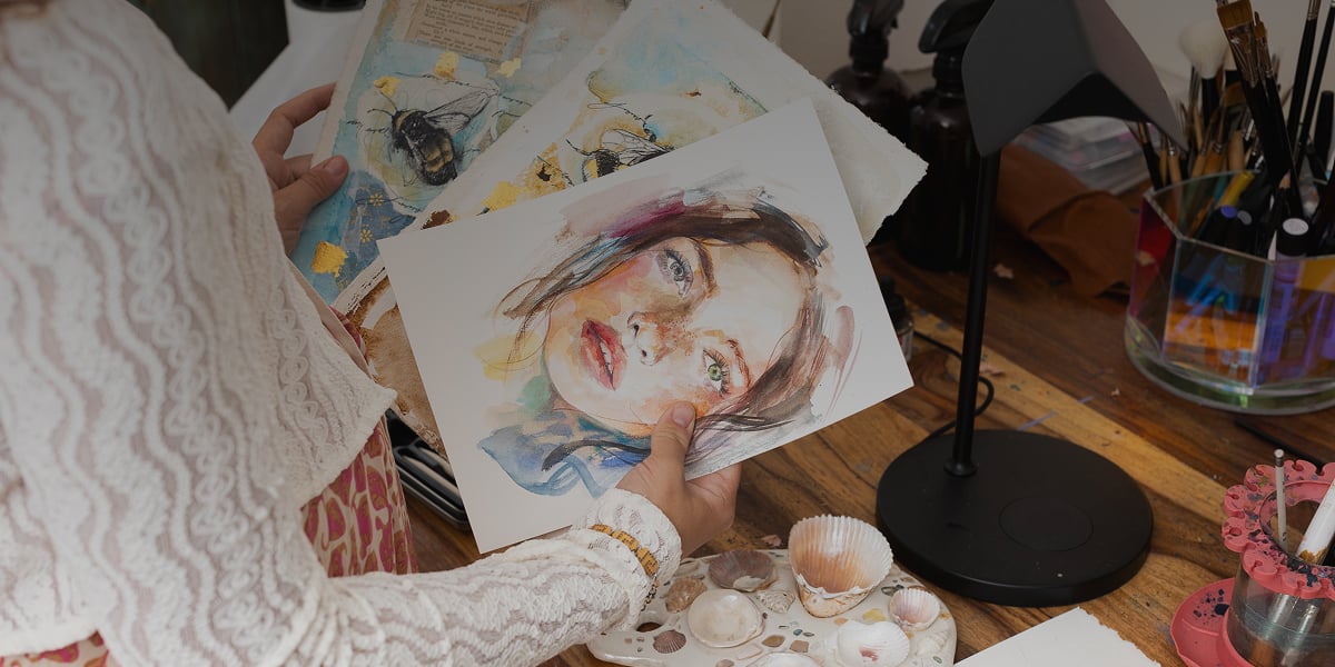 woman holding watercolor papers with portrait